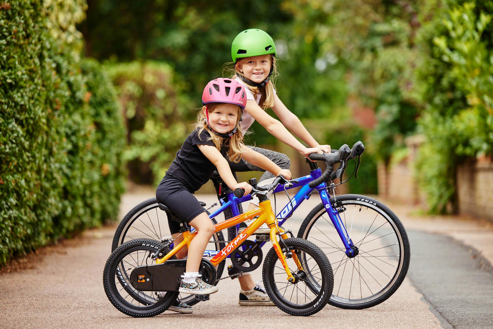 Two smiling girls on their bikes in summer