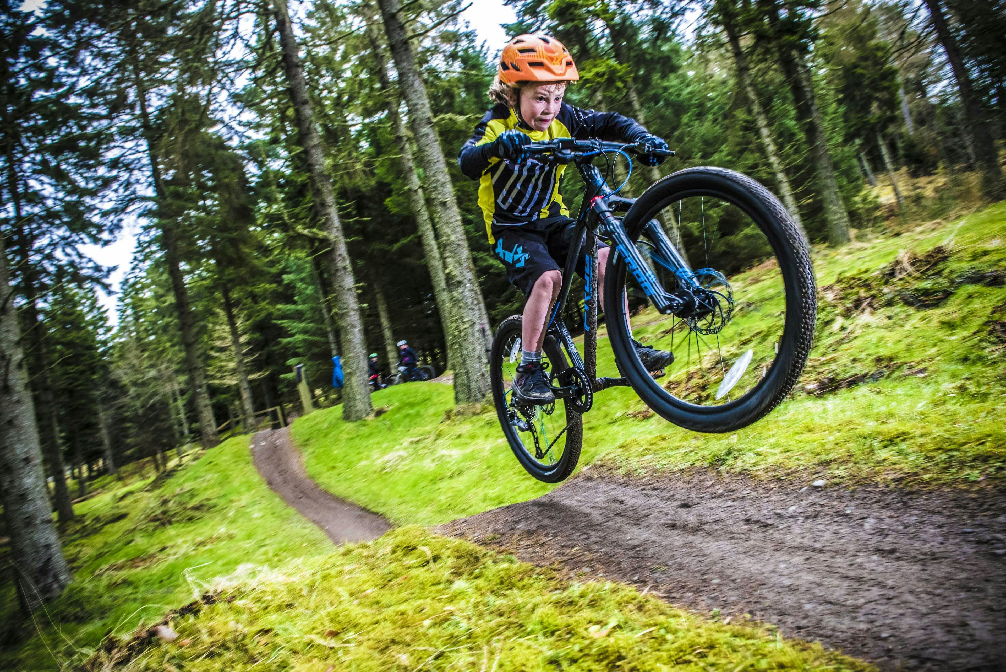 Boy performing a jump on a mountain bike course