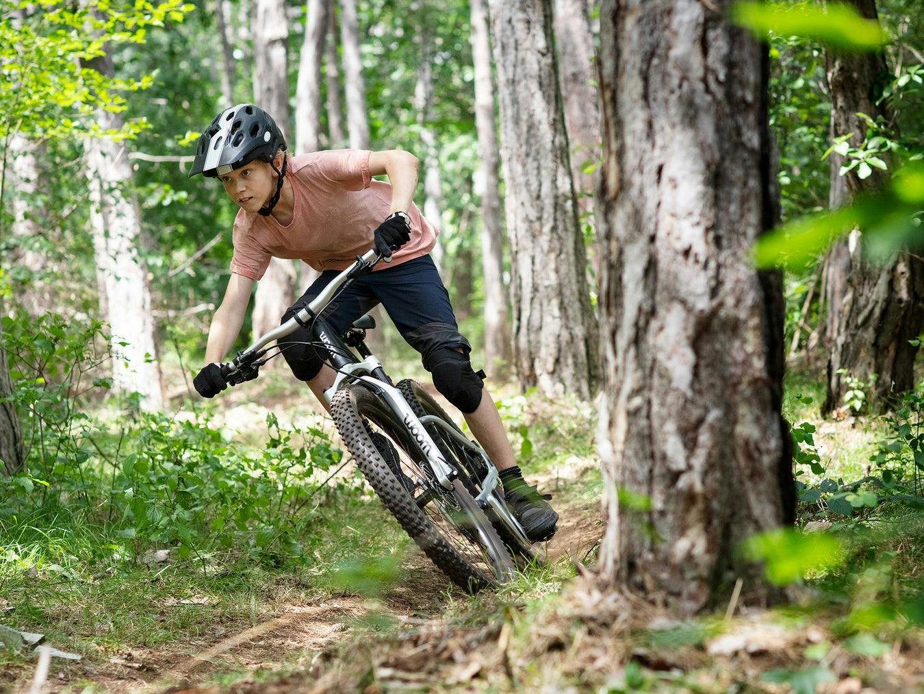 child riding a Woom 6 in woods - bike club
